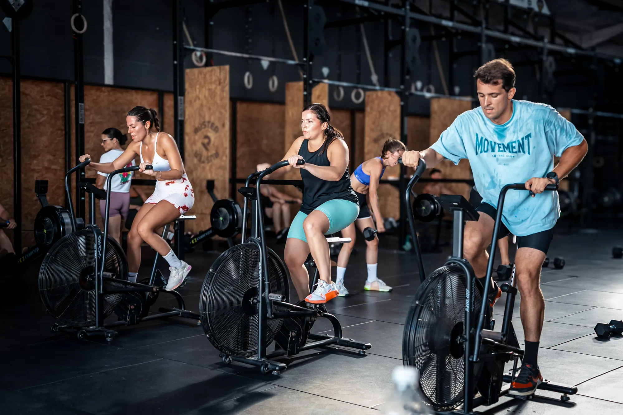 Grupo de personas entrenando en fila sobre assault bikes durante una clase en Feel Training Club Sevilla